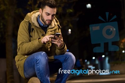 Portrait Of Young Man Using His Mobile Phone On The Street At Ni… Stock Photo