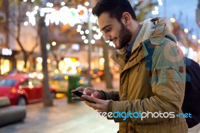 Portrait Of Young Man Using His Mobile Phone On The Street At Ni… Stock Photo