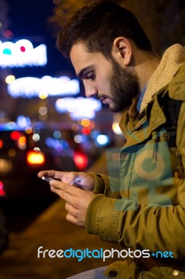 Portrait Of Young Man Using His Mobile Phone On The Street At Ni… Stock Photo