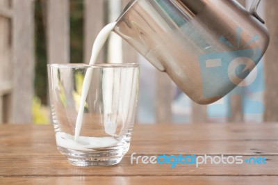 Pour Milk From A Pitcher Into A Glass Stock Photo