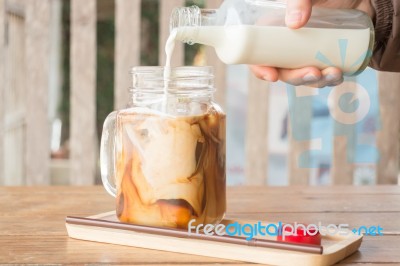 Pouring Milk To Iced Glass Of Coffee Stock Photo