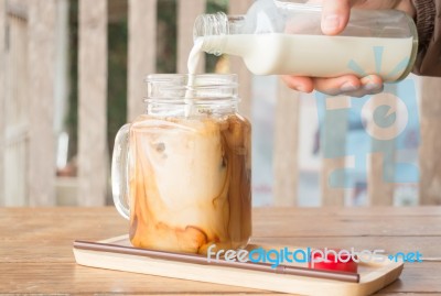 Pouring Milk To Iced Glass Of Coffee Stock Photo