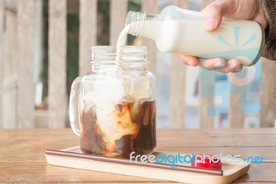 Pouring Milk To Iced Glass Of Coffee Stock Photo