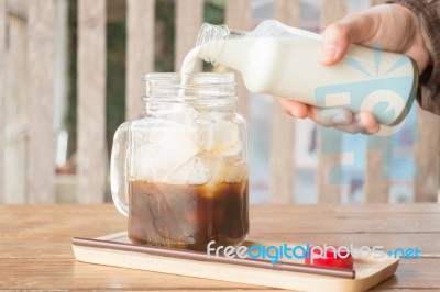 Pouring Milk To Iced Glass Of Coffee Stock Photo