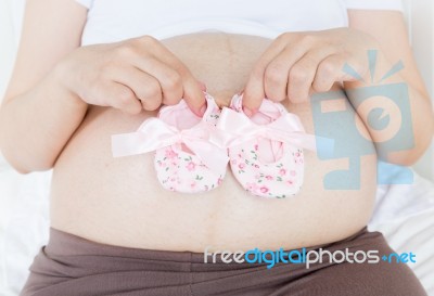 Pregnant Belly With A Pair Of Pink Shoes Stock Photo