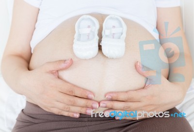 Pregnant Belly With A Pair Of White Shoes Stock Photo