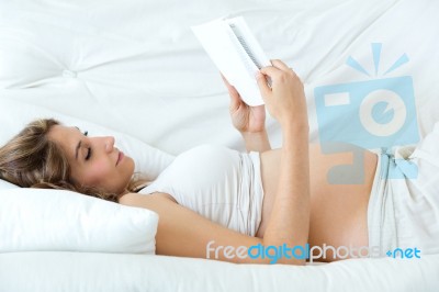 Pregnant Woman Reading A Book On Sofa Stock Photo