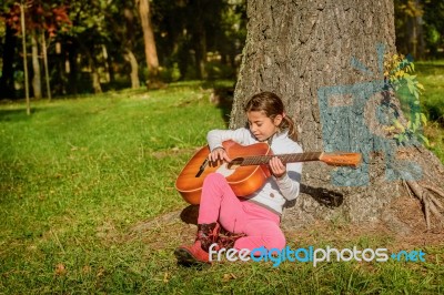 Pretty  Little Girl Playing Guitare In The Park Stock Photo