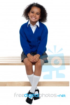 Pretty School Girl Seated Comfortably On A Bench Stock Photo