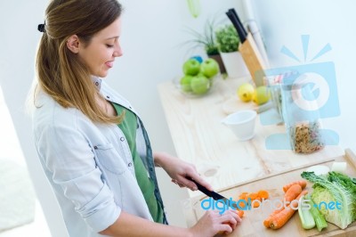 Pretty Young Woman Cutting Vegetables In The Kitchen Stock Photo