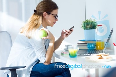 Pretty Young Woman Eating An Apple And Working At Home Stock Photo