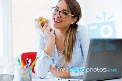 Pretty Young Woman Eating An Apple In Her Office Stock Photo