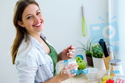 Pretty Young Woman Eating Yogurt In The Kitchen Stock Photo