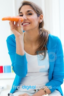 Pretty Young Woman Having Fun With A Carrot In The Kitchen Stock Photo