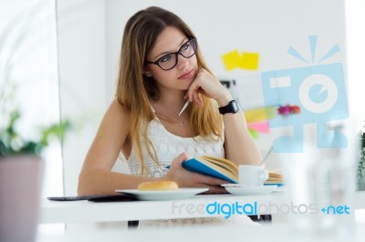 Pretty Young Woman Reading A Book And Having Breakfast At Home Stock Photo