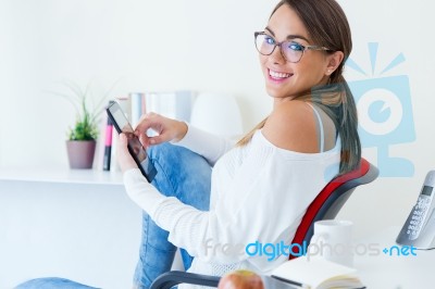 Pretty Young Woman Using Her Mobile Phone In The Office Stock Photo