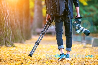 Professional Photographer With Camera And Tripod In Autumn Stock Photo