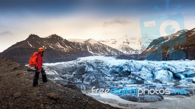 Professional Photographer With Camera And Tripod In Winter. Professional Photographer Looking To Glacier In Iceland Stock Photo