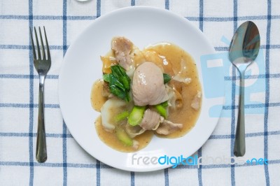 Rad Na, Famous Thai Chinese Style Wide Rice Noodle Dish With Tasty Tender Pork With Thick Gravy Sauce. Flat Lay With Spoon And Fork Stock Photo