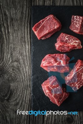 Raw Angus Beef Slices On The Black Stone  On The Wooden Table Vertical Stock Photo