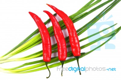 Red Chili Peppers And Green Onions With Water Drops Isolated On Stock Photo