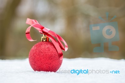 Red Christmas Bauble With Bow Outdoors In Snow Stock Photo