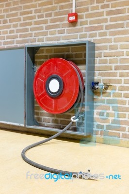 Red Fire Hose On Reel At Wall Stock Photo