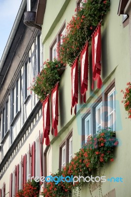 Red Geraniums And Flags On A House In Rothenburg Stock Photo