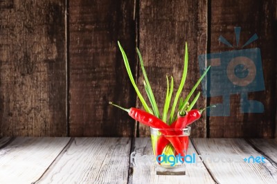 Red Hot Chilli Peppers And Green Onions In Glass Of Water Stock Photo