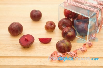 Red Plum Fruit With Measuring Tape In Glass Bowl Stock Photo