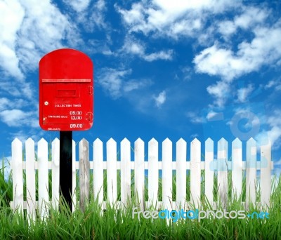 Red Postbox With White Fence Stock Photo