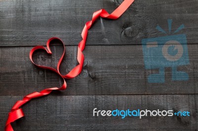 Red Ribbon In Heart Shape On Wooden Background Stock Photo