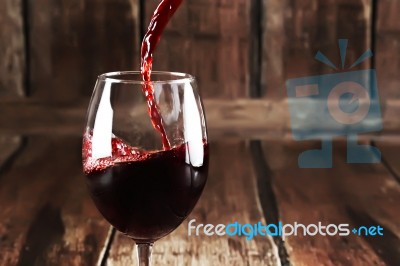 Red Wine Is Poured From Bottle To Glass Stock Photo