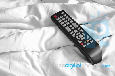 Remote On Bed Sheets Stock Photo