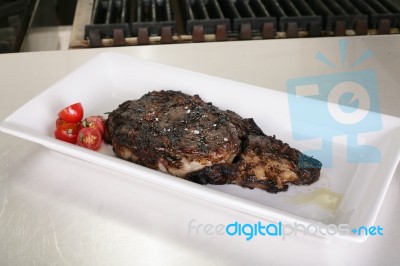 Rib-eye Steak Resting On The Plate In The Kitchen Ready To Serve… Stock Photo