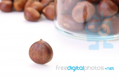 Roasted Chestnuts Outside Bottle On White Floor Stock Photo