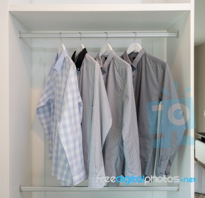 Row Of Shirts Hanging In White Wardrobe Stock Photo