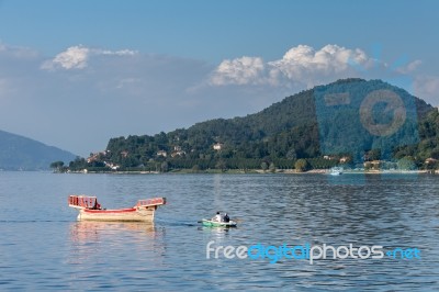 Rowing Boat Pulling A Traditional Boat On Lake Maggiore Piedmont… Stock Photo