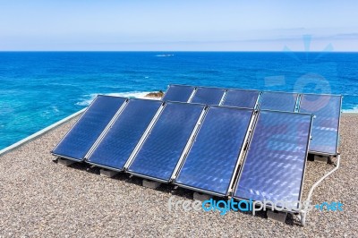 Rows Of Solar Collectors On Roof At Sea Stock Photo