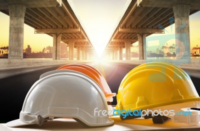 Safety Helmet On Civil Engineering Working Table Against Bridge Construction In Urban Scene Stock Photo