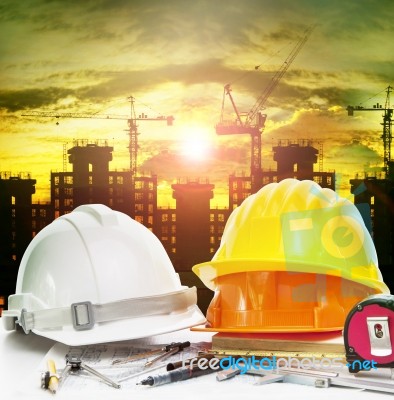 Safety Helmet On Engineer Working Table And Construction Site Background Stock Photo