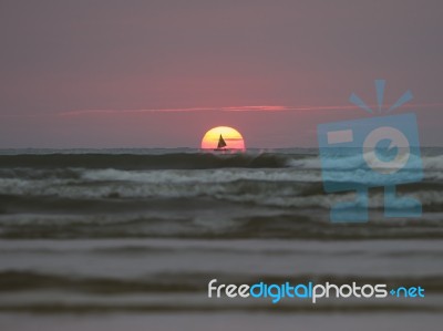 Sailing Boat And Sun Rising In Sea Stock Photo