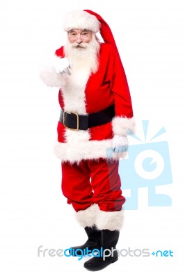 Santa Indicating Finger At Camera In Full Length Stock Photo