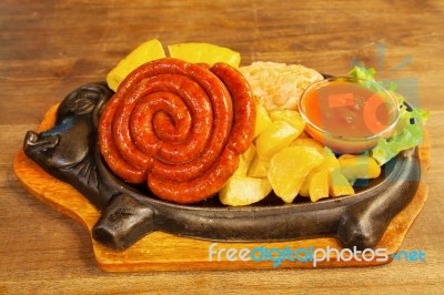 Sausage With Potatoes, Vegetables And Hot Sauce On A Plate Stock Photo