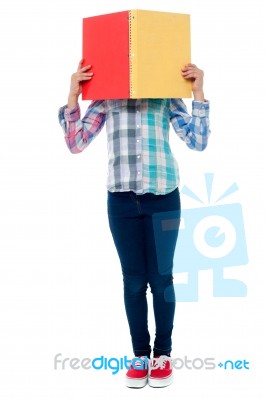 School Girl Hiding Her Face Behind A Notebook Stock Photo