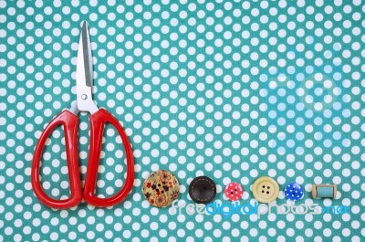 Scissors And Buttons On Blue Polka Dot Fabric Background Stock Photo