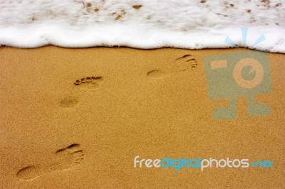 Sea Wave With Foam And Human Footprints On Sand Stock Photo