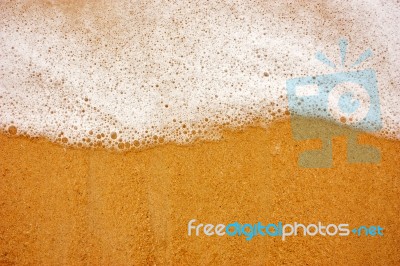 Sea Wave With Foam On Sand Stock Photo