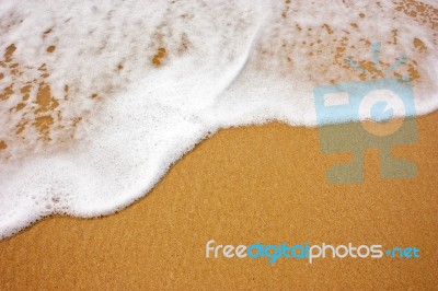 Sea Wave With Foam On Sand Stock Photo