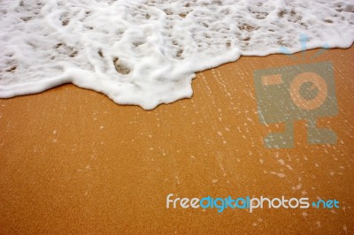 Sea Wave With Foam On Sand Stock Photo